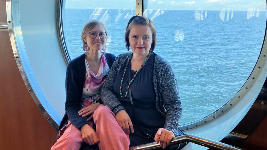 Jenni Sillantaka ja Päivi Sormunen istuvat laivan pyöreällä ikkunalla. featured-image