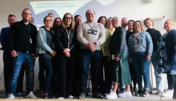 Yhteiskuva työpajan hymyilevistä noin 20 osallistujasta.